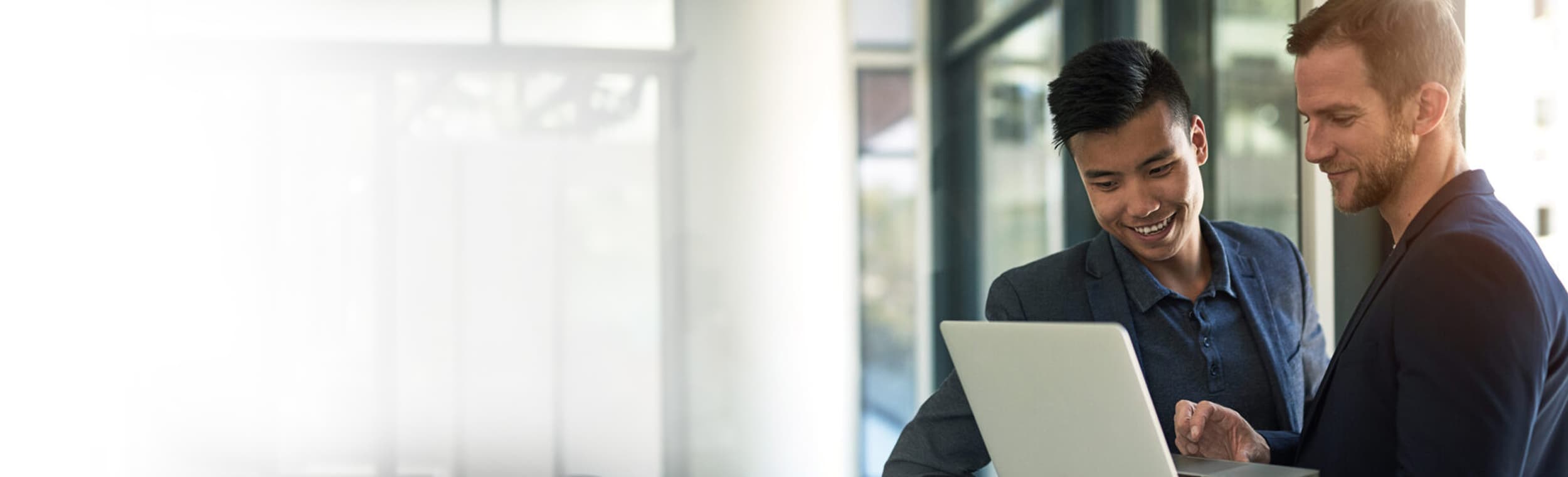 Two employees looking at a laptop 1200x699
